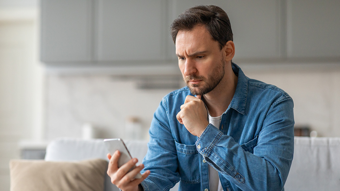 man on sofa looking at his phone