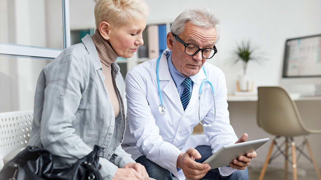 Two physicians look at medical records on tablet